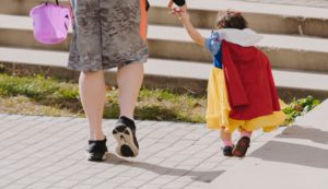 Child in costume holding an adult's hand